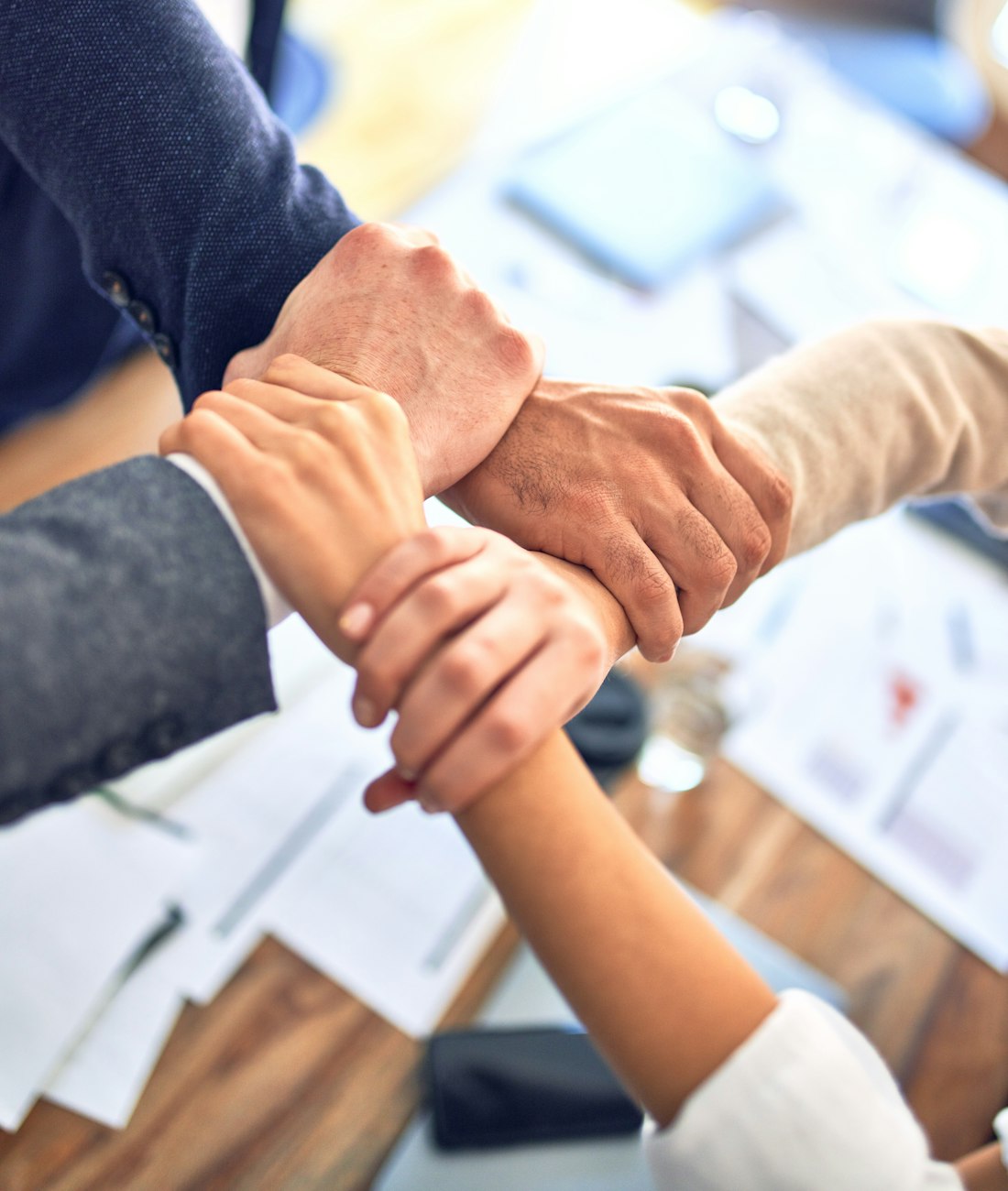Manos de un equipo de trabajo unidas sobre una mesa de junta, símbolo de colaboración